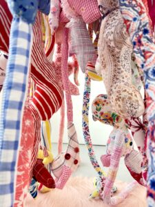 A side view of a suspended soft sculpture made from colourful second-hand textiles.