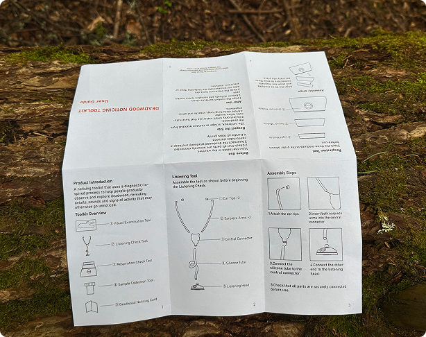 Printed instruction guide for the Deadwood Noticing Toolkit opened on the surface of deadwood outdoors.