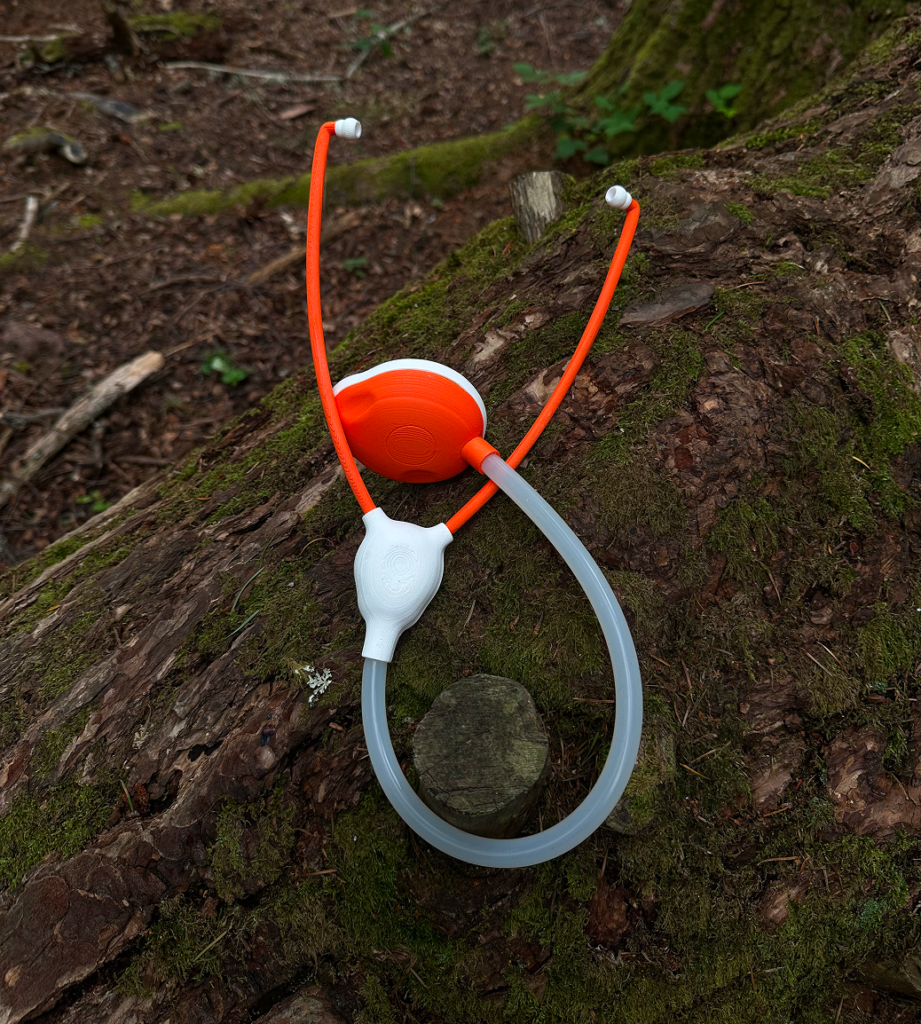 Orange listening device placed on deadwood with connected tubing and earpieces.