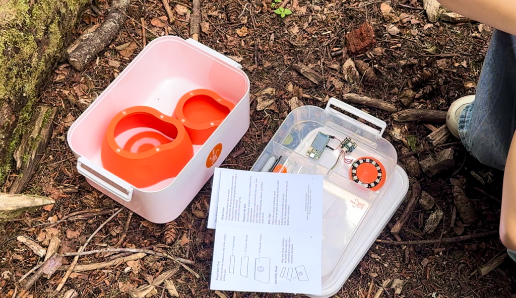 Deadwood Noticing Toolkit with its tools, instruction sheet and storage box arranged on the woodland floor.