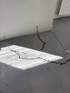 Detail of suspended handwritten material casting shadows across the gallery floor in The Uncanny: What Remains