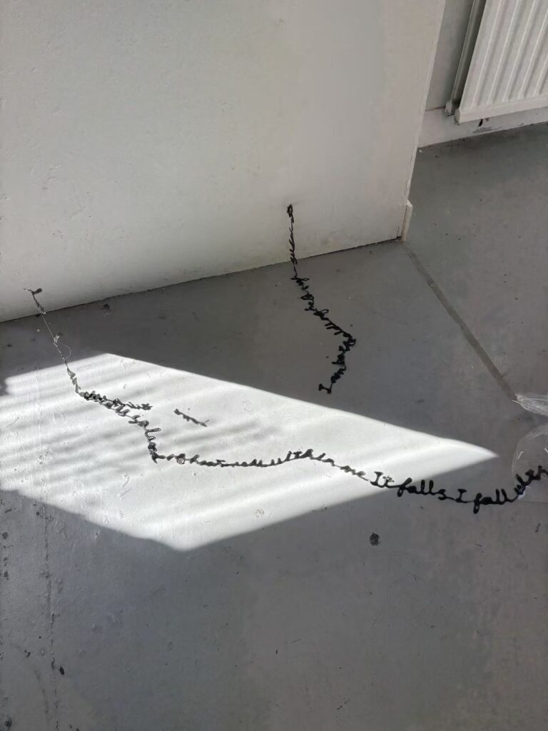 Detail of suspended handwritten material casting shadows across the gallery floor in The Uncanny: What Remains