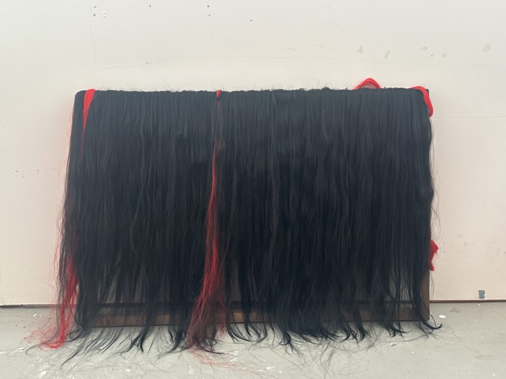 Projection‑screen installation Haptic Strands; video projected onto fabric layered with black and red hair strands.
