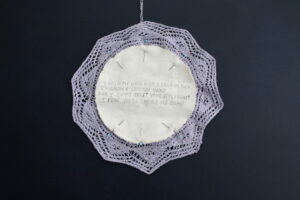 A hand-knitted lace doily on a dark blue background.