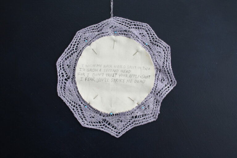 A hand-knitted lace doily on a dark blue background.