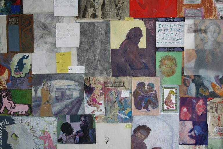 A photo of multiple drawings and paintings tacked to the wall.