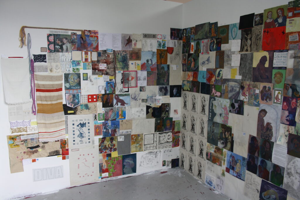 A photo of multiple drawings and paintings tacked to the wall.