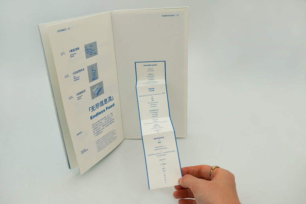 An open publication showing the Endless Feed family while a hand holds a long folded paper strip extending downward from the right page. The strip contains bilingual trigger, trace and sequence information.